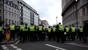 Londra, Inghilterra, Regno Unito - 20 marzo 2021: La polizia fa la guardia mentre i manifestanti si avvicinano a Langham Place durante la dimostrazione delle restrizioni di blocco del Coronavirus.