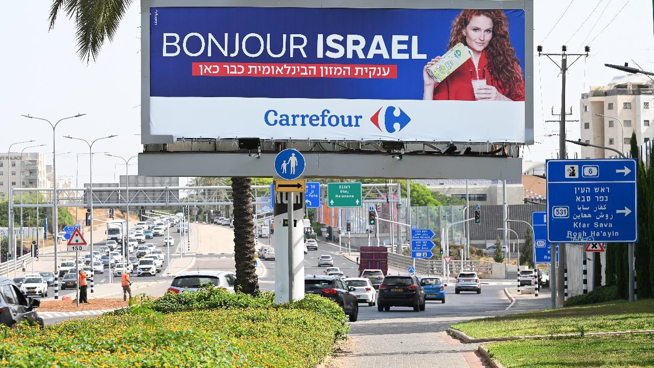 HERZLIYA, ISRAELE – 24 MAGGIO 2023: Un cartellone pubblicitario lungo il lato di una strada principale annuncia l'apertura della catena di supermercati francese Carrefour. Il gruppo francese di vendita al dettaglio ha aperto circa 50 negozi in Israele